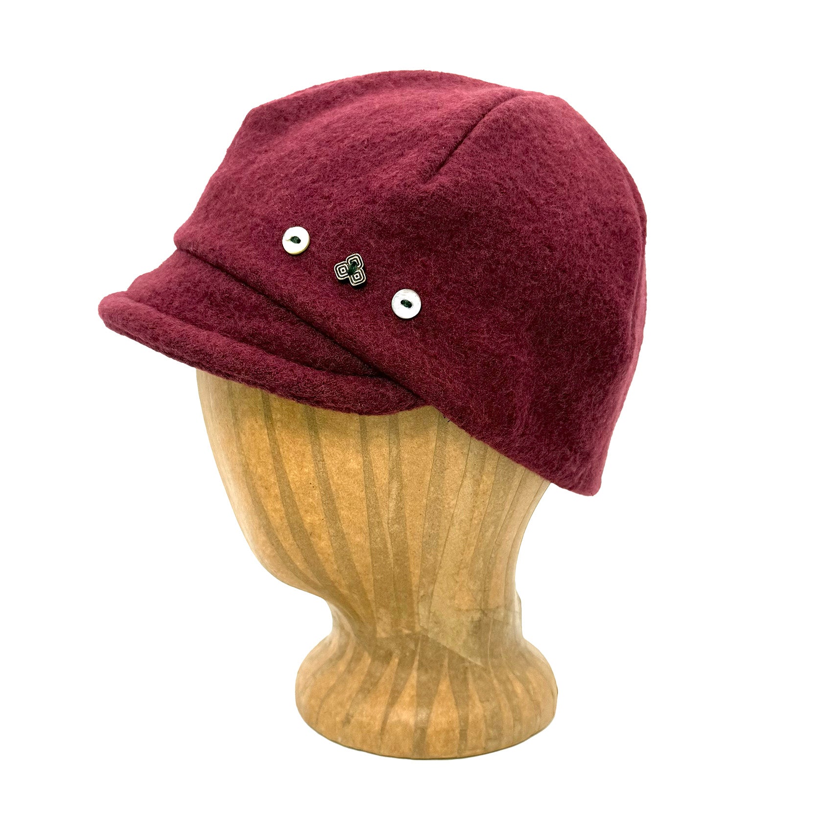 Burgundy knit cap with decorative buttons on a wooden mannequin head against a white background g-and-l-positive-goods-camden-cap-left-side