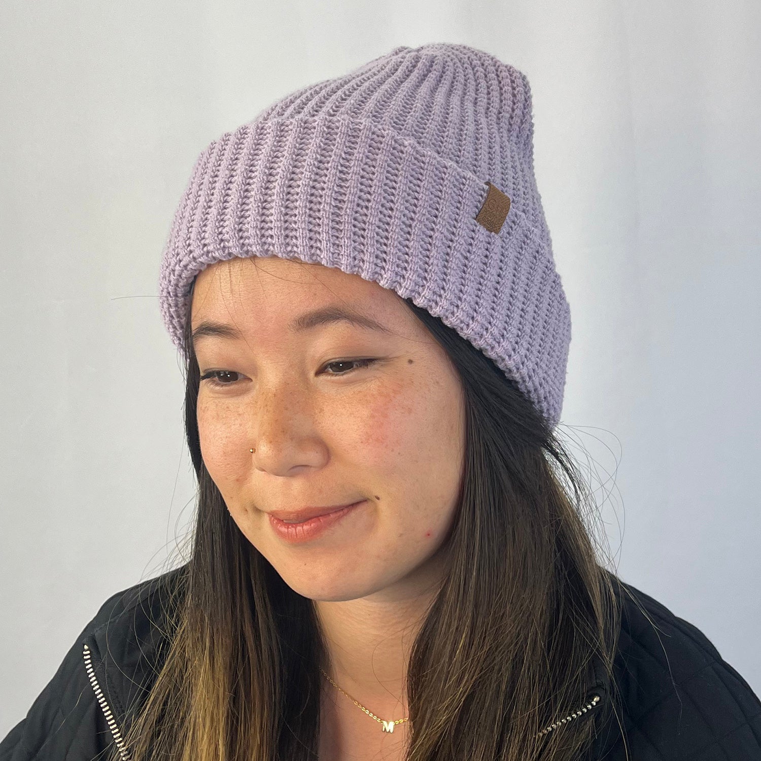 Person wearing a light lavender knit beanie with a logo on a plain background
g-and-l-positive-goods-kayo-beanie-female-model