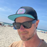 Male model styling front view of the La Playa Riviera Trucker Hat under the sun