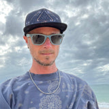 Male model styling the Visions Cosmos Trucker Hat, highlighting adjustable mesh back and eco-friendly vibe.