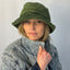 Woman wearing a green bucket hat and gray coat against a plain background   Polar Fleece fabricl – upcycled unisex winter hat