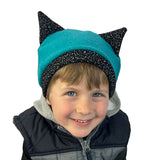 Kritter Beanie in Bahama teal blue-green with white speckles on black, on boy model – recycled cotton beanie with cat ears
