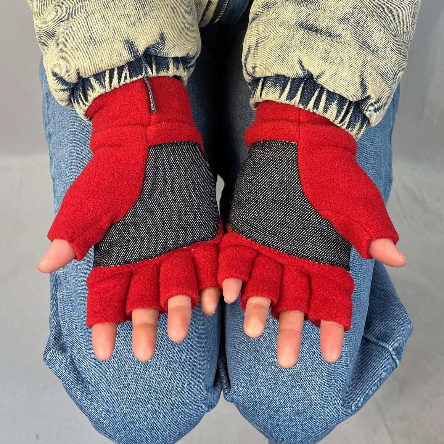 Red fingerless gloves with with denim palm worn by a person on a plain background for men and women Upcycled polar fleece
