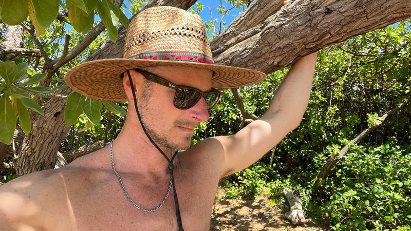 Male model styling profile view of Sundaze Palm Straw Sun Hat, demonstrating unisex natural sun hat.