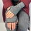 Person wearing black and grey striped fingerless gloves with a maroon jacket and gray pants.