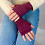 Person wearing burgundy fingerless gloves with a neutral background
