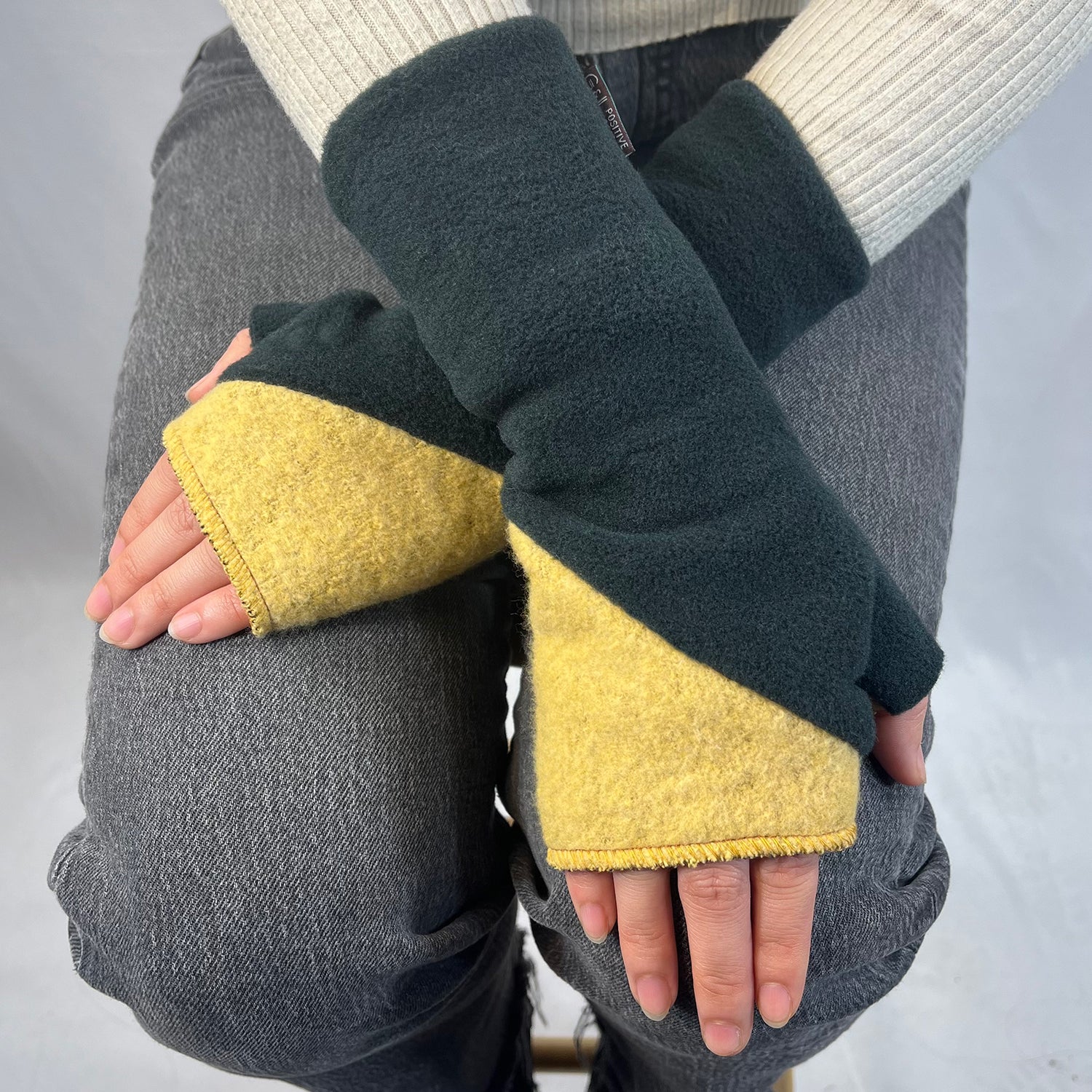Person wearing black and yellow fingerless gloves on a neutral background