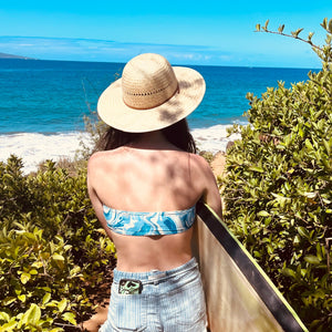 Female model wearing Hana Palm Sun Hat, showcasing from the back the wide brim and palm straw weave.