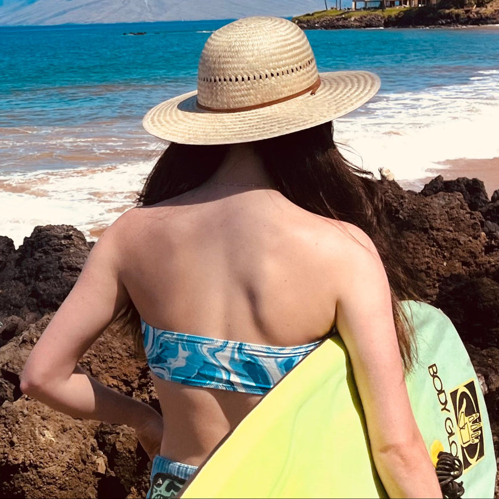 Female model wearing Hana Palm Straw Sun Hat, showcasing wide brim and eco-friendly materials.