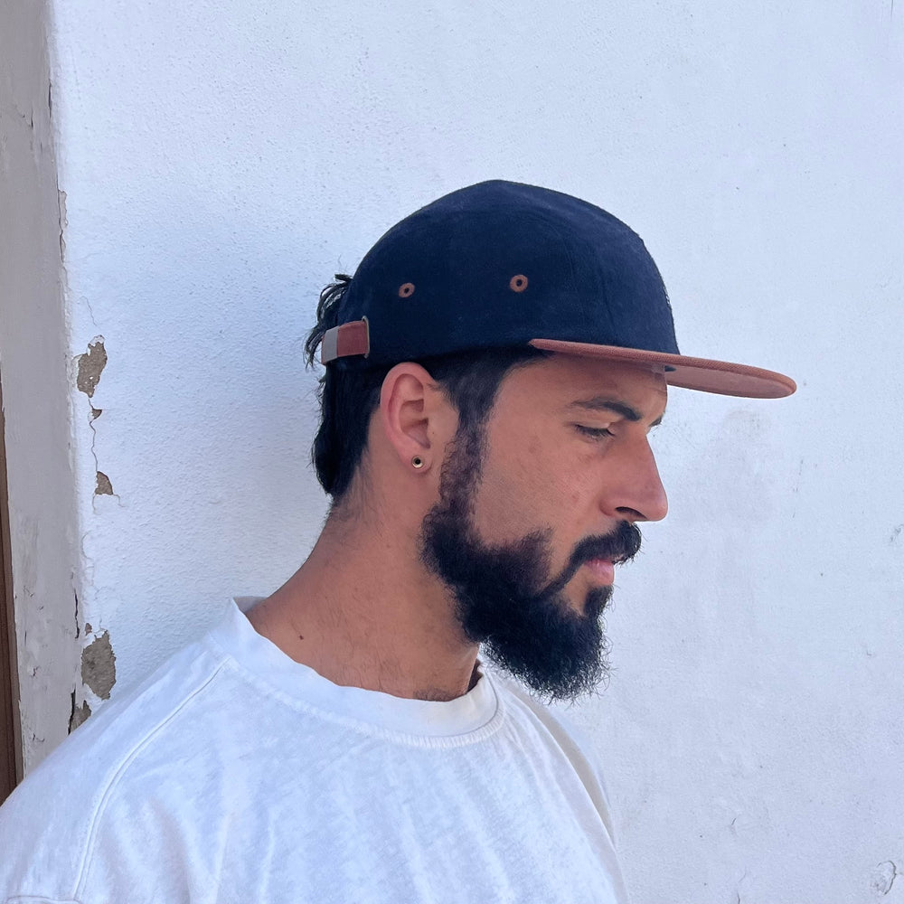 Male model styling profile view of the Kamp 5 Panel Camp Hat with organic cotton and contrast brim in Lagos, Portugal