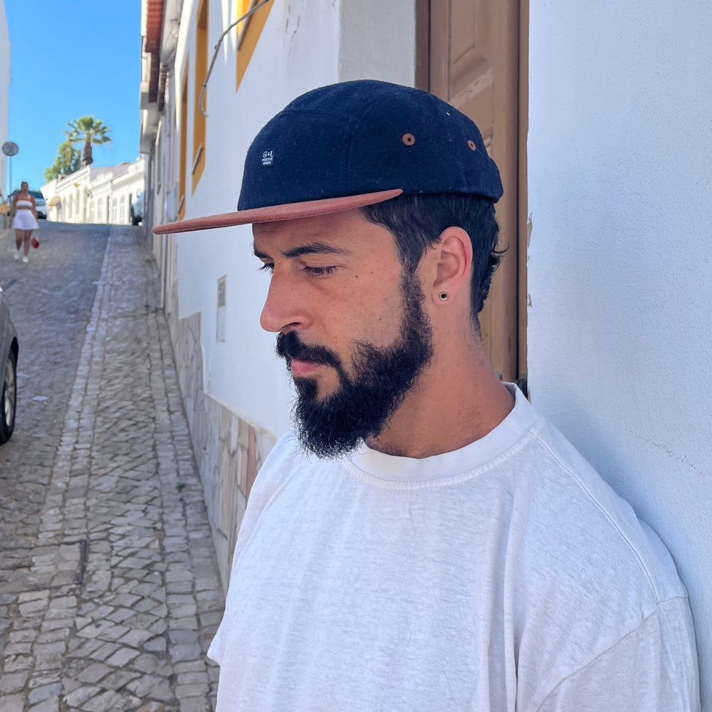 Male model styling three-quarter view of the Kamp 5 Panel Camp Hat with organic cotton and contrast brim in Lagos, Portugal
