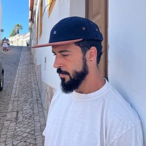 Male model styling three-quarter view of the Kamp 5 Panel Camp Hat with organic cotton and contrast brim in Lagos, Portugal