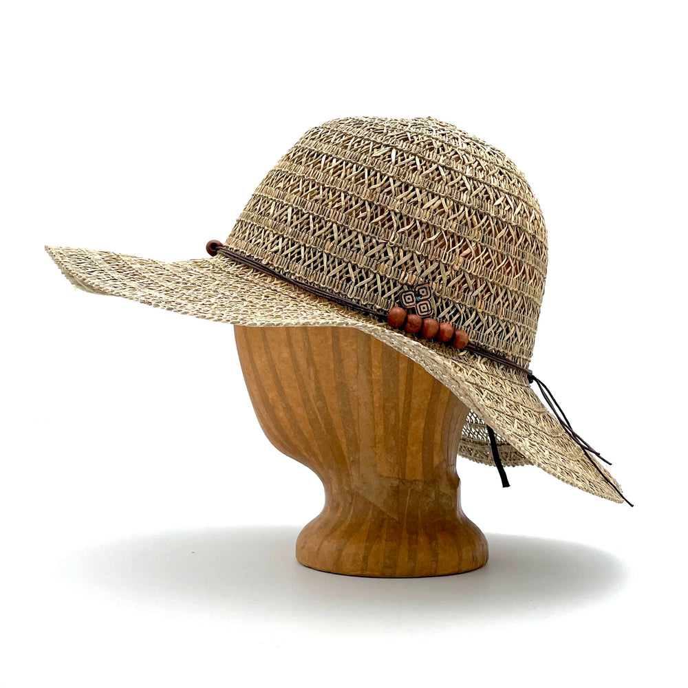 Martinique Sun Hat side view on wooden head block made of grass straw with breathable weave and wood bead band