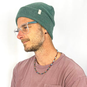 Male model wearing teal Midnight Beanie – eco-friendly knit hat
