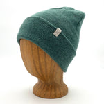 Midnight Beanie in teal color – worn on wooden head block.