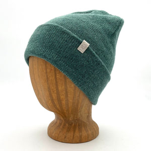 Midnight Beanie in teal color – worn on wooden head block.