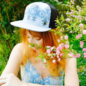 Female model wearing the Nu Tribe Grey Trucker Hat, showcasing unisex eco-friendly design and Southwestern print.