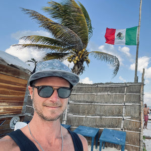 Male model styling the Nu Tribe Grey Trucker Hat, highlighting its adjustable fit, breathable mesh, and stylish pattern.