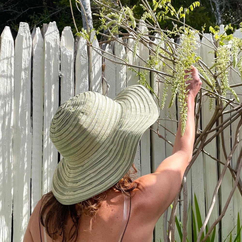 Quito Sun Hat zoomed back view of Cactus color, modeled by female highlighting travel-friendly design