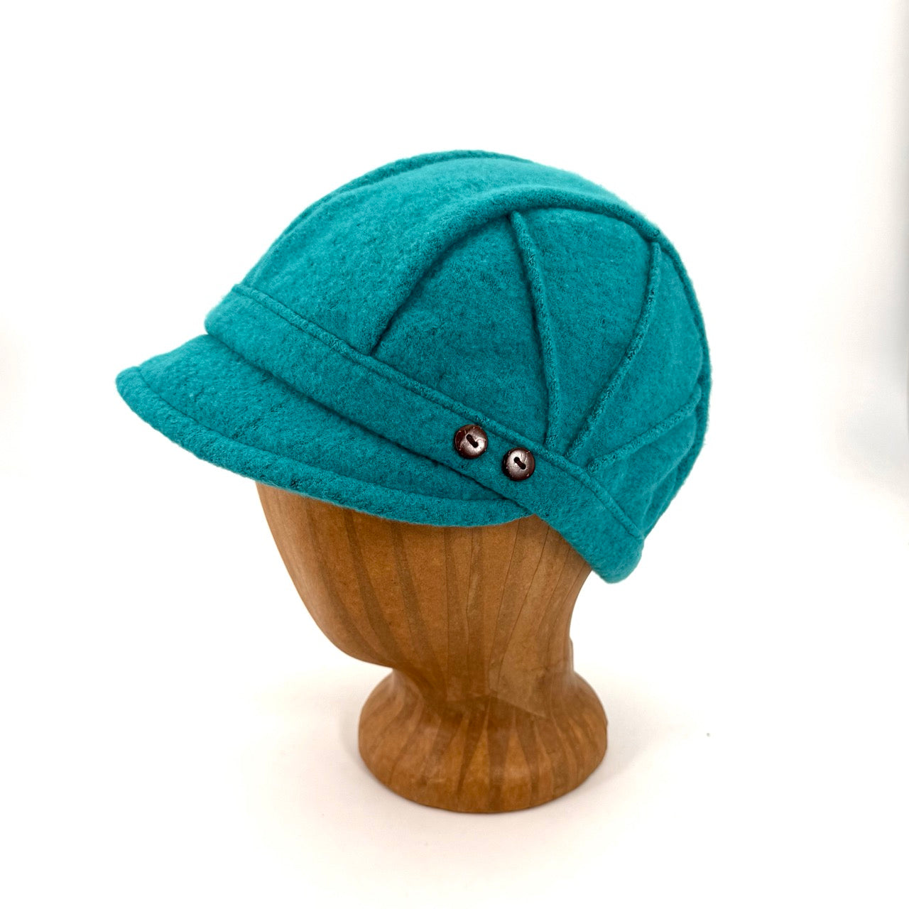 A teal green felt cloche hat displayed on a wooden mannequin head against a white background.