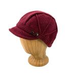 A burgundy wool cap with a curved brim and two dark metal buttons, displayed on a light wood mannequin head against a white background.