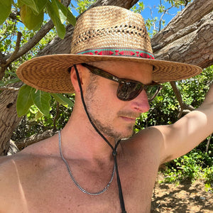 Male model styling profile view of Sundaze Palm Straw Sun Hat, demonstrating unisex natural sun hat.
